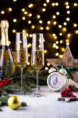 Two glasses of sparkling champagne at New year eve night with clock and bokeh background. Christmas decoration dinner table setting, copy space