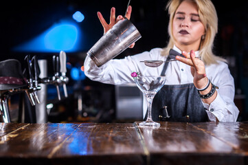 Girl barman mixes a cocktail in the alehouse