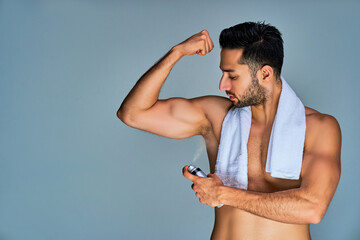 Strong guy with black hair with a beard with a raised hand puffs deodorant under the arm. Cosmetics concept