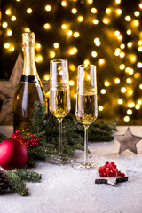 Two glasses of sparkling champagne at New year eve night with clock and bokeh background. Christmas decoration dinner table setting, copy space