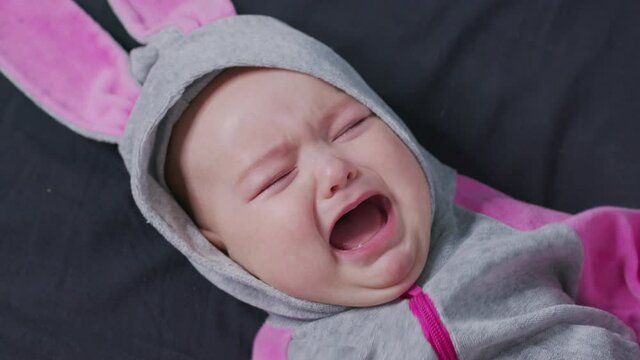 A Baby Lies on the Bed and Cries. Child is Upset and Crying.