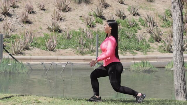 Hembra hermosa hace ejercicio al frente de una laguna en el parque en verano 