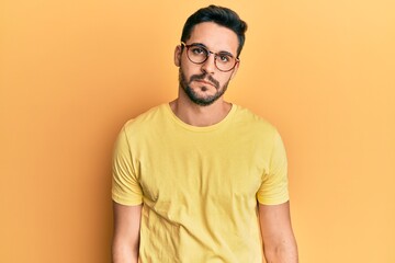 Obraz premium Young hispanic man wearing casual clothes and glasses relaxed with serious expression on face. simple and natural looking at the camera.