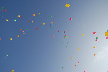 Knowledge Day holiday in St. Petersburg.
Clear white blue sky with a railing. There are a couple of dozen balloons filled with helium in the sky. The balls fly into the open sky. Balls of different co
