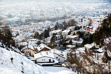 Fototapeta na wymiar Innstruck in winter, Austria. Beautiful aerial view, house roofes covered with snow, Alps mountains on the background.