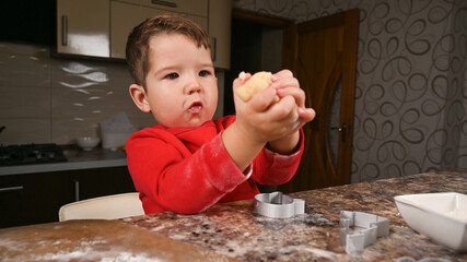 The child holds a piece of dough in his hands