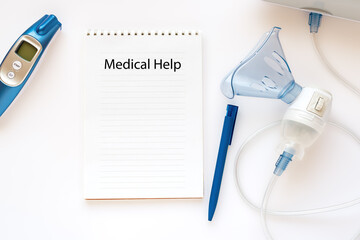 inscription in a notebook - medical help, near infrared thermometer and nebulizer