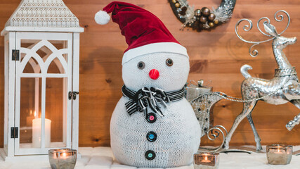 Snowman in a red cap and lights with wooden background. Christmas decoration