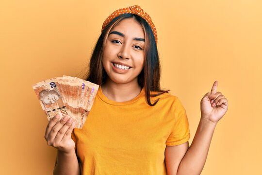 Young latin woman holding south african rand banknotes smiling happy pointing with hand and finger to the side