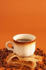 classic cup of coffee in orange surface with coffee beans