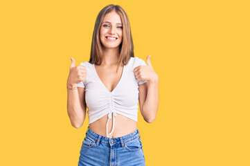 Young beautiful blonde woman wearing casual white tshirt success sign doing positive gesture with hand, thumbs up smiling and happy. cheerful expression and winner gesture.