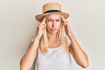 Young blonde girl wearing summer hat with hand on head, headache because stress. suffering migraine.