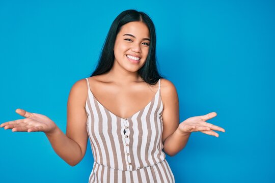 Young beautiful asian girl wearing casual clothes clueless and confused expression with arms and hands raised. doubt concept.