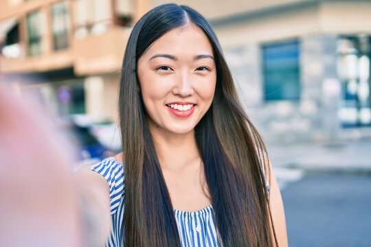 Young chinese woman smiling happy making selfie by the camera at street of city.