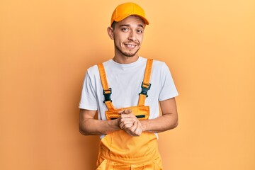 Young hispanic man wearing handyman uniform skeptic and nervous, disapproving expression on face with crossed arms. negative person.