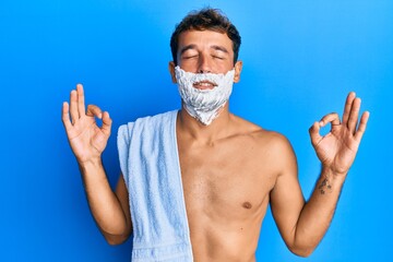 Handsome man saving beard with shave foam over face relax and smiling with eyes closed doing...