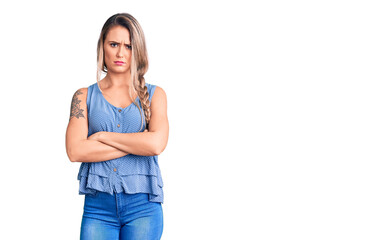 Young beautiful blonde woman wearing casual sleeveless t-shirt skeptic and nervous, disapproving expression on face with crossed arms. negative person.