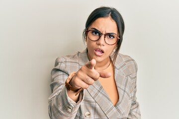 Young brunette woman wearing business jacket and glasses pointing displeased and frustrated to the camera, angry and furious with you