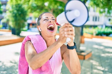 Middle age sportswoman screaming using megaphone at the park