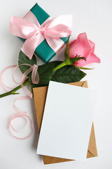 bouquet of pink roses and gift box on white table
