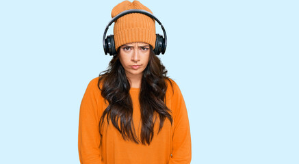Beautiful brunette young woman listening to music using headphones skeptic and nervous, frowning upset because of problem. negative person.