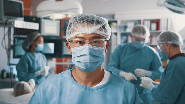 Portrait of professional asian mixed race surgeon doctor wearing medical respiratory mask working in hospital room during coronavirus covid-19 pandemic.