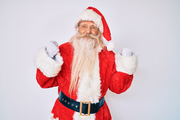 Old senior man with grey hair and long beard wearing santa claus costume with suspenders excited for success with arms raised and eyes closed celebrating victory smiling. winner concept.