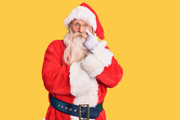 Old senior man with grey hair and long beard wearing traditional santa claus costume pointing to the eye watching you gesture, suspicious expression