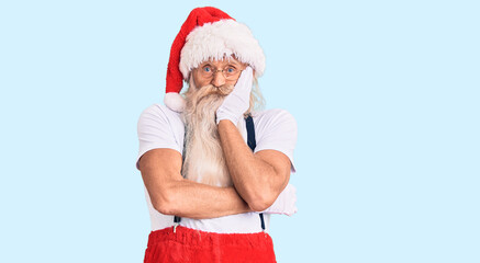 Old senior man with grey hair and long beard wearing santa claus costume with suspenders thinking looking tired and bored with depression problems with crossed arms.