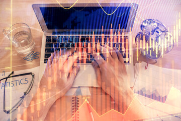 Double exposure of man's hands typing over laptop keyboard and forex chart hologram drawing. Top view. Financial markets concept.