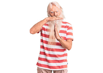Old senior man with grey hair and long beard wearing striped tshirt doing time out gesture with...