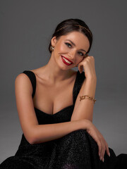 Breast up portrait of young elegant sexy woman in black shiny evening dress with decolette against...