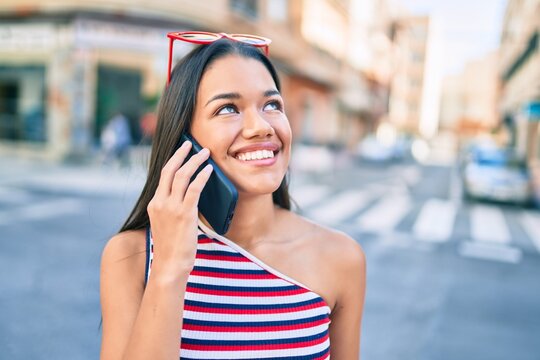 Young latin girl smiling happy talking on the smartphone at the city.
