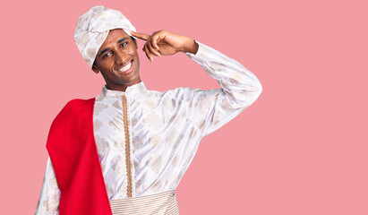 African handsome man wearing tradition sherwani saree clothes smiling pointing to head with one finger, great idea or thought, good memory