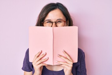 Young beautiful woman wearing glasses reading book smiling and laughing hard out loud because funny crazy joke. - obrazy, fototapety, plakaty