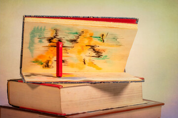 A Red Pastel Chalk Stick Holds Open a Artists Sketch Book