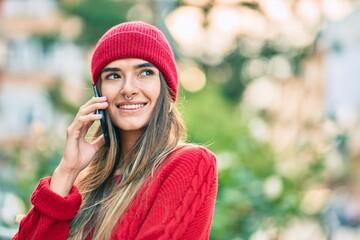 Young hispanic woman wearing winter style talking on the smartphone at the city.