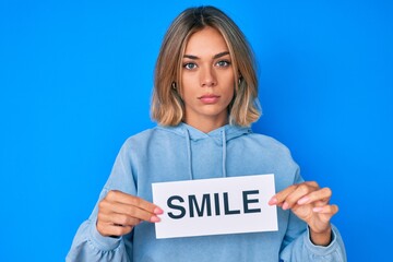 Beautiful caucasian woman holding smile text relaxed with serious expression on face. simple and natural looking at the camera.