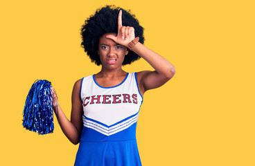 Young african american woman wearing cheerleader uniform holding pompom making fun of people with...