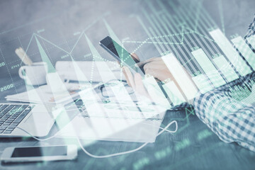 Double exposure of man's hands holding and using a digital device and forex graph drawing. Financial market concept.