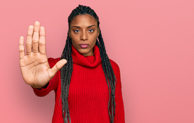 African american woman wearing casual winter sweater doing stop sing with palm of the hand. warning...