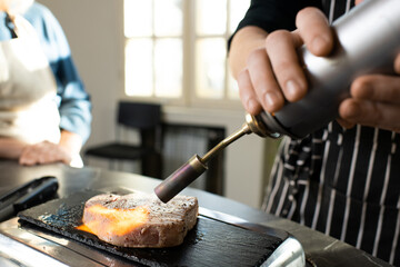 Hand of young male cooking coach in apron smoking piece of boiled beef