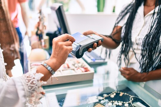 Woman paying purchase using credit card and dataphone at clothing store.