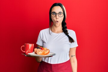 Young hispanic woman wearing waitress apron holding tray with breakfast smiling with an idea or question pointing finger with happy face, number one