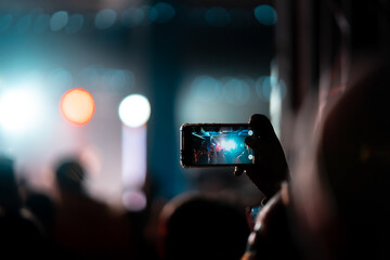 Person close up of recording video with smartphone during a concert.