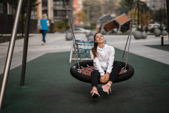 Young woman rides on a swing at the playground.