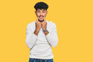 Fototapeta na wymiar Young arab man wearing casual winter sweater smiling with open mouth, fingers pointing and forcing cheerful smile