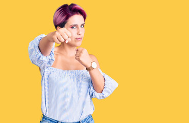 Fototapeta na wymiar Young beautiful woman with pink hair wearing casual clothes punching fist to fight, aggressive and angry attack, threat and violence
