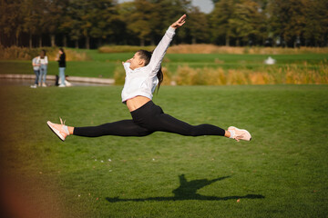 Sport girl jumping in the air on nature demonstrate perfect stretching.