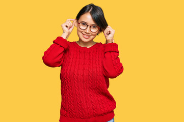 Young beautiful hispanic woman with short hair wearing casual sweater and glasses smiling pulling ears with fingers, funny gesture. audition problem